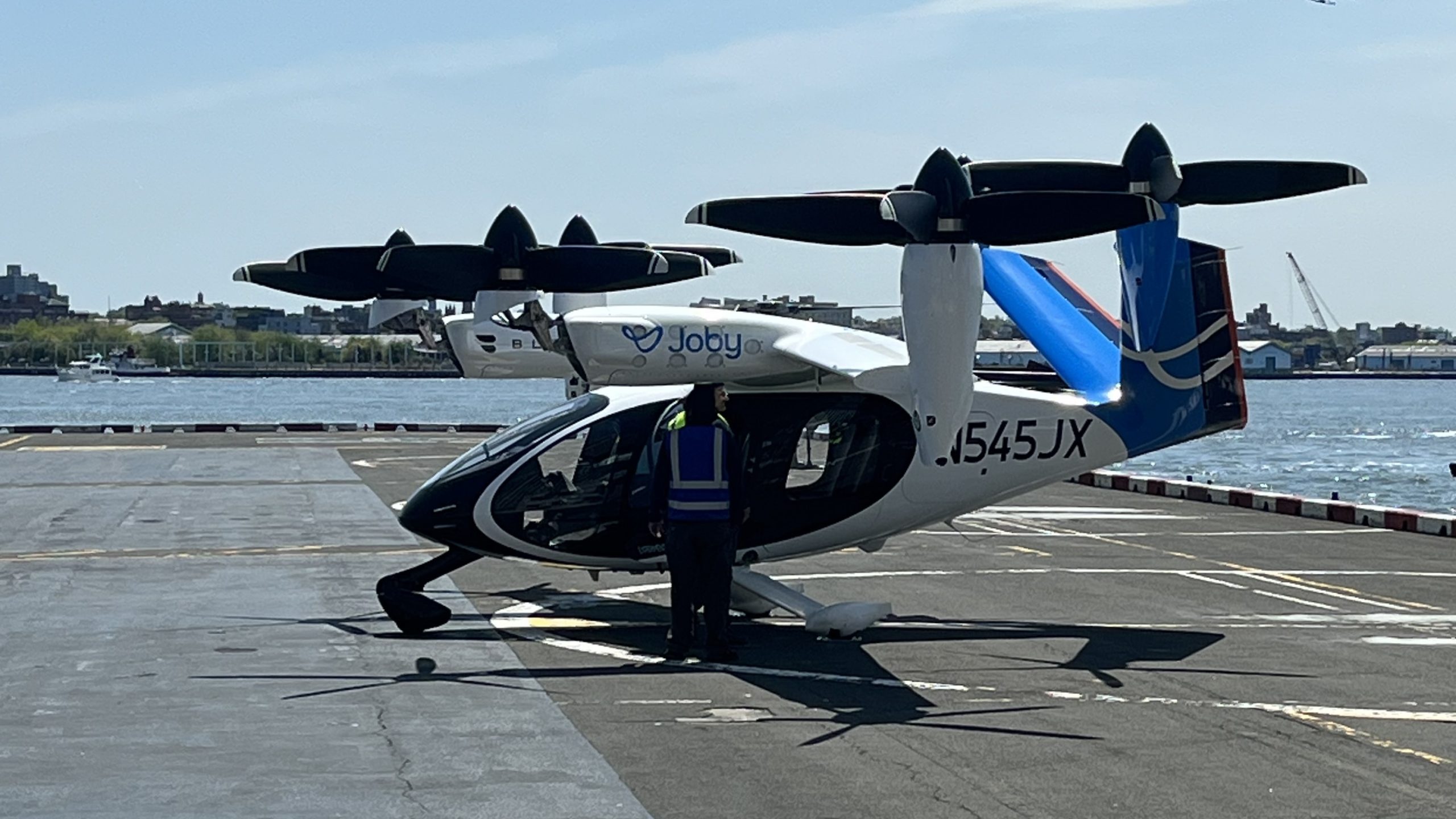 Joby S4 eVTOL aircraft (N545JX) on a New York City helipad with waterfront in the background